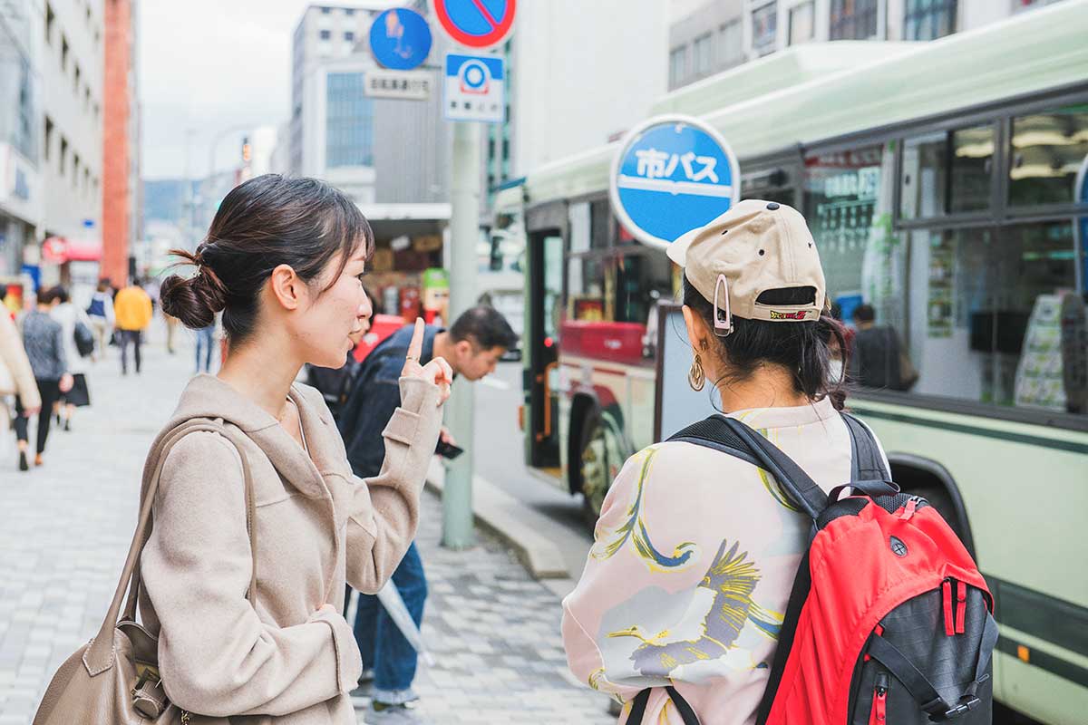 ゲストにバス停とバスの乗り方を教えるMakiさん