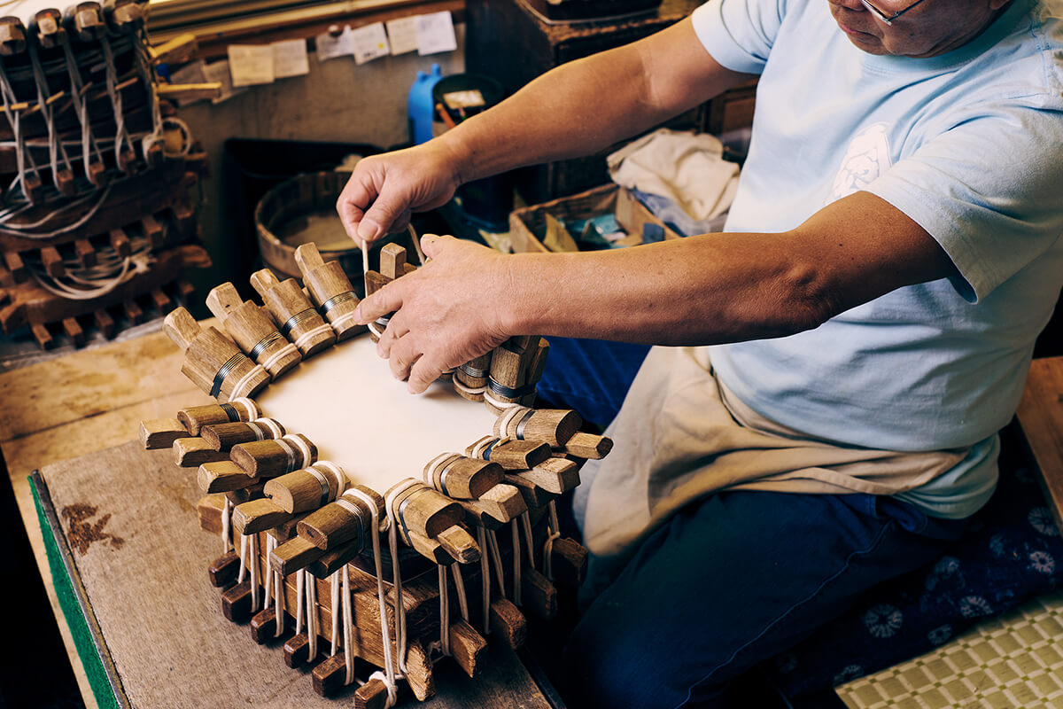 『皮張り』作業の様子。『木セン』というクリップのような道具で皮を挟み、『胴』と呼ばれる木製のボディに張っていく。